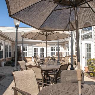 A sunny outdoor patio area with tables, chairs, and large umbrellas.