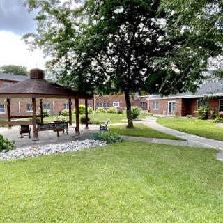 A peaceful garden area featuring a gazebo, pathways, and lush greenery.