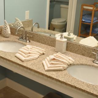 A clean bathroom with a double sink, neatly arranged towels, and a large mirror.