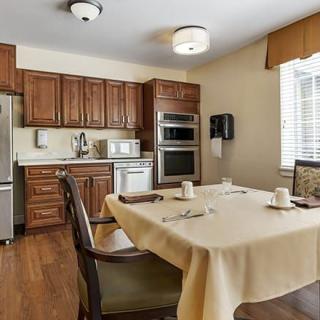 A cozy kitchen and dining area with wooden cabinets and a table set for two.