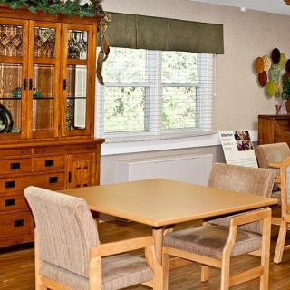 A cozy dining room with a wooden table and chairs, featuring a large wooden cabinet and decor by the window.