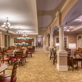 An elegant dining area with chandeliers, tables, and columns.