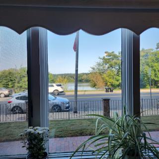 A serene view from the window showcasing a flag, green landscape, and passing cars.