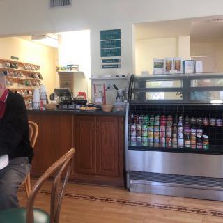 A cozy cafe interior with a drink display and seating area.