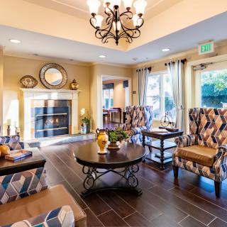A cozy living room with traditional decor featuring a fireplace, chandelier, and comfortable seating.