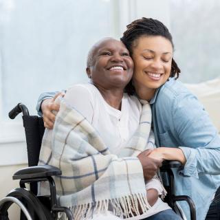 A joyful moment shared between two people, one in a wheelchair and the other embracing them warmly.
