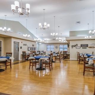 A spacious dining room with neatly arranged tables and elegant chandeliers.