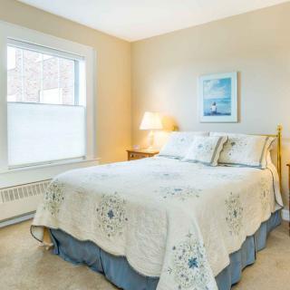 Cozy bedroom with a bed, lamp, window, and wall art.