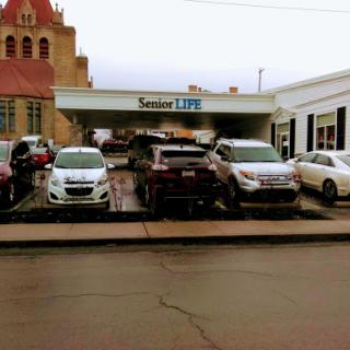 A view of a busy parking lot with various vehicles parked underneath a covered area.