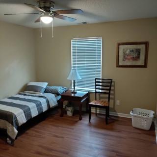 A cozy bedroom with a single bed, striped bedding, and wooden flooring.