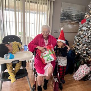 A joyful Christmas celebration with family, featuring gift giving and festive attire.