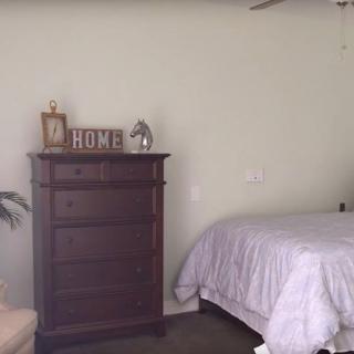 A cozy bedroom with a wooden dresser and neatly made bed.