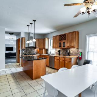 A modern kitchen with wooden cabinets, an island, and a dining area.