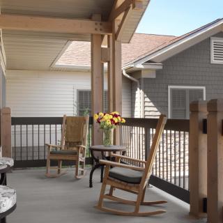 A cozy porch with rocking chairs and a table adorned with flowers.