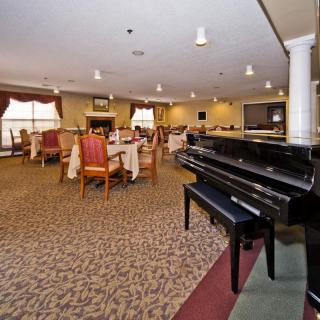 A spacious dining area with a grand piano, featuring elegantly set tables and comfortable seating.