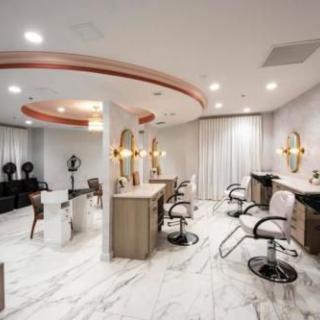 A modern salon interior featuring stylish chairs, mirrors, and elegant lighting with a marble floor design.
