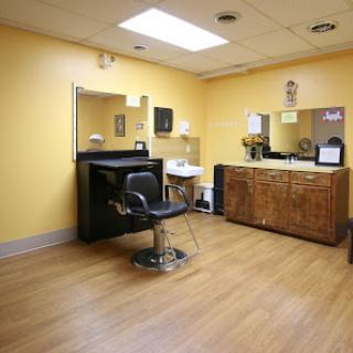 A cozy salon space featuring a styling chair and wooden cabinets against a cheerful yellow backdrop.
