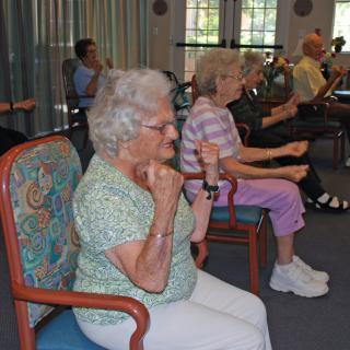 Seniors participating in a seated exercise class together.
