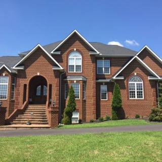 A large brick house with a well-maintained lawn under a clear blue sky.