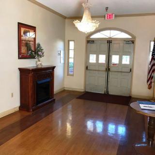 A quiet lobby featuring double doors, a wooden floor, an American flag, and a decorative fireplace.