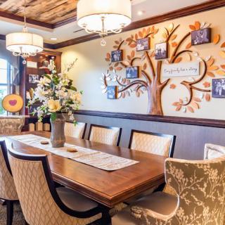 An elegantly designed dining room featuring a wooden table, upholstered chairs, and a family tree wall art.