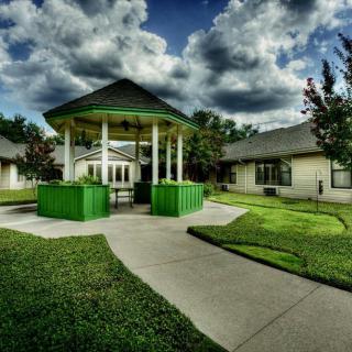 A vibrant green gazebo in a park setting under a cloudy sky.