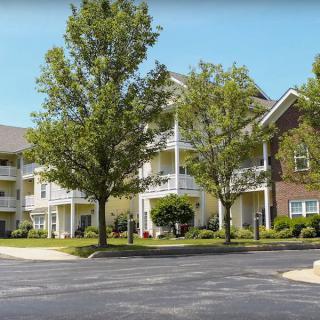 A residential apartment complex with trees and well-maintained landscaping.