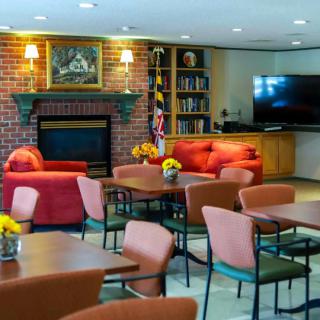 A cozy lounge area featuring comfortable seating, a fireplace, television, and bookshelves.