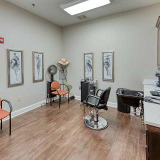 A cozy hair salon with stylish decor, featuring chairs, a workstation, and framed artwork on the walls.