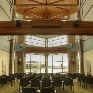 A modern conference room with rows of empty chairs and large windows providing natural light.