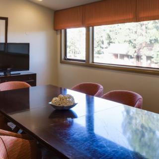 A meeting room with a large table, several chairs, and a television.