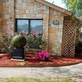 A charming residence featuring a stone exterior and vibrant flowers in the garden.