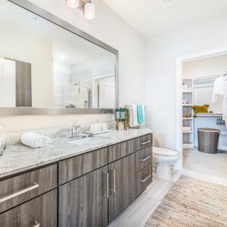 A modern bathroom featuring a large mirror, stylish cabinetry, and a clean, bright aesthetic.