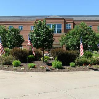 A brick building with neatly landscaped surroundings and American flags.