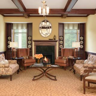 A cozy and elegantly designed living room featuring comfortable armchairs, a central coffee table, and a warm fireplace.