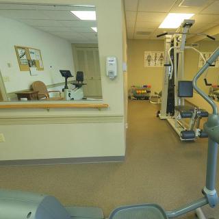 A small gym room with various exercise equipment and a mirror reflecting the space.