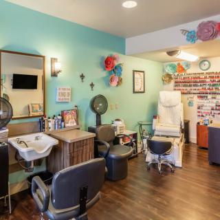 A well-decorated beauty salon with styling chairs, mirrors, and a variety of nail polishes on display.