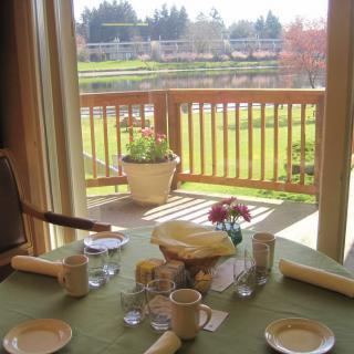 A dining table set for a meal with a view of a balcony and lush greenery in the background.