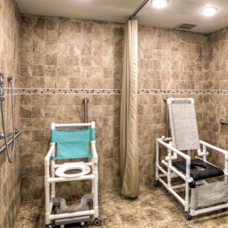 An accessible bathroom equipped with shower chairs and privacy curtain.