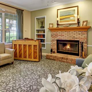 A cozy living room featuring a brick fireplace, piano, and comfortable seating.