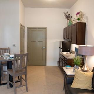A modern apartment interior featuring a kitchenette, dining area, and living space.