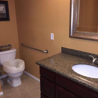 A clean and organized bathroom with a granite countertop and a mounted mirror.