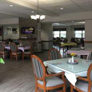 A spacious dining area with neatly arranged tables and chairs, well-lit by a chandelier.