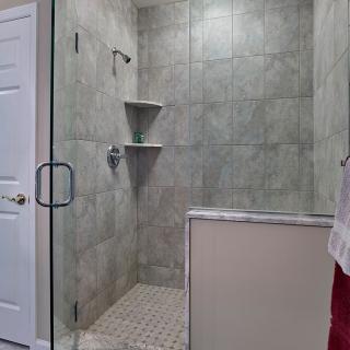 A modern tiled shower with a glass door and built-in shelves.