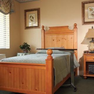 A cozy bedroom with a wooden bed and matching nightstand, featuring framed artwork on the walls.
