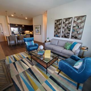 A modern living room with vibrant decor, featuring a comfortable sofa and armchairs, a colorful rug, and contemporary artwork.