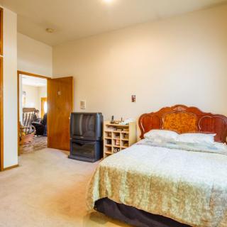 A cozy bedroom with a large bed, wooden headboard, vintage television, and nightstand.