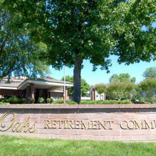 Entrance sign to a retirement community surrounded by trees and landscaping.