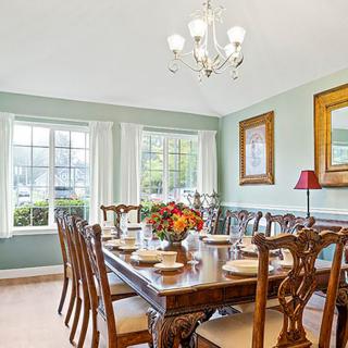 A well-decorated dining room with a large table, elegant chairs, and a chandelier.
