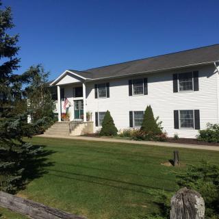 A white residential house with a neatly maintained lawn and surrounding trees.